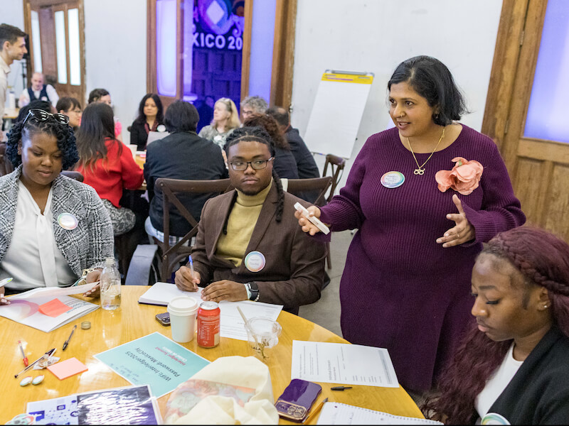 Four participants seated around a table in discussion during a workshop on instant payment systems and financial inclusion.